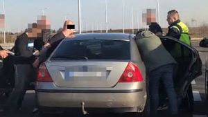 Osobowe auto z którego policjanci zatrzymują trzech mężczyzn.