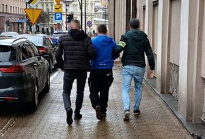Policjanci prowadzą zatrzymanego mężczyznę.