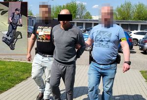 Policjanci prowadzą zatrzymanego mężczyznę.