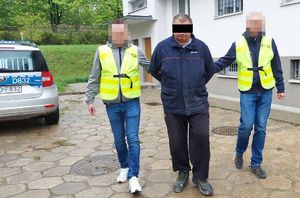 policjanci prowadzą zatrzymanego 54-latka