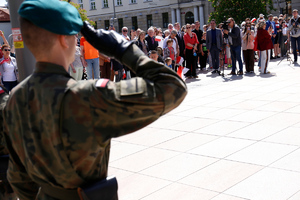 Salutujący żołnierz oraz mieszkańcy obserwujący uroczystość.