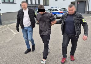 policjanci prowadzą zatrzymanego sprawcę rozboju