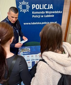 policjant rozmawia z osobami przy policyjnym stoisku