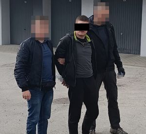 policjanci prowadzą zatrzymanego mężczyznę