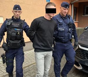 policjanci prowadzą zatrzymanego mężczyznę
