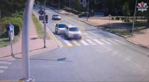 Dwa pojazdy biorące udział w zdarzenia drogowym stojące na skrzyżowaniu dróg w tle inne pojazdy i zabudowa miejska