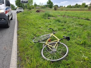 Zderzenie rowerzysty z osobówką. Rower leżący na trawie, obok pojazd osobowy