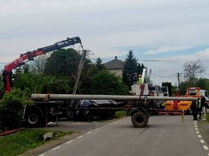 pracownicy pogotowia energetycznego przy podnoszeniu przewróconego słupa