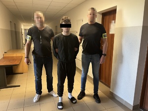 Dwóch nieumundurowanych policjantów z zatrzymanym mężczyzną