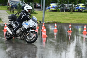 Policjant pokonuje tor przeszkód na motocyklu służbowym policji.