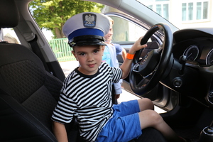 dziecko w radiowozie w policyjnej czapce
