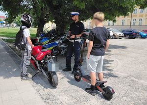 policjant podczas kontroli jednośladów. Dwóch nastolatków kontrolowanych przez policjanta