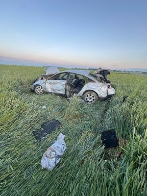 rozbity pojazd w zbożu i elementy pojazdu porozrzucane na polu