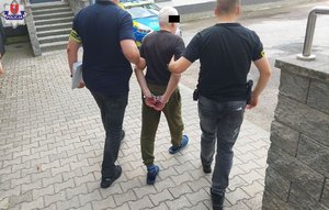 zatrzymany prowadzony przed dwóch policjantów w cywilnym ubraniu