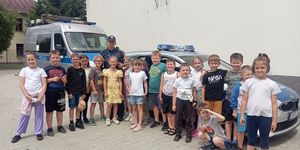 dzieci z policjantką przed radiowozami
