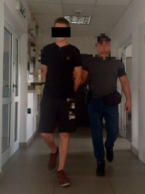 nieumundurowany policjant prowadzi korytarzem zatrzymanego mężczyznę