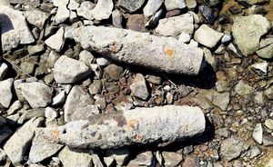 Dwa pociski artyleryjskie leżące na kamieniach