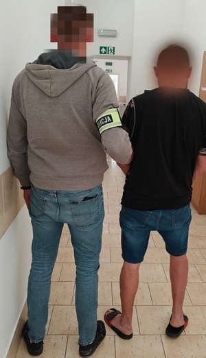 policjant prowadzi zatrzymanego sprawcę przemocy domowej