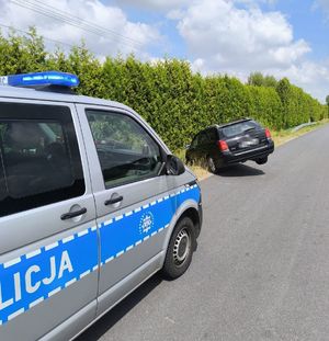 czarna toyota stojąca przodem w rowie za nią bus policyjny