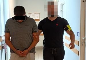 policjant prowadzi poszukiwanego mężczyznę