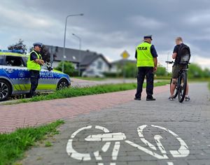dwaj policjanci na chodniku stojący obok nich chłopak na rowerze