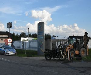 Zderzenie motocykla z koparką. Obok radiowóz na miejscu zdarzenia