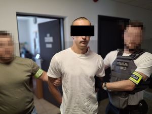 dwóch nieumundurowanych policjantów z zatrzymanym mężczyzną