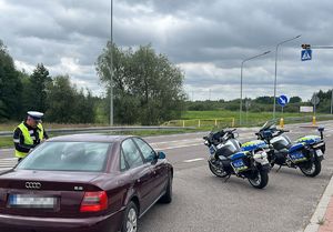 Policjant prowadzi kontrolę drogową pojazdu.