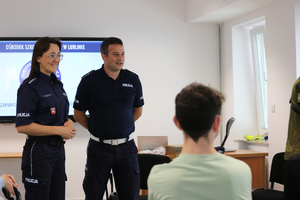 Zdjęcie przedstawia dwoje policjantów, którzy rozmawiają z dziećmi z domu dziecka o pracy policjanta.