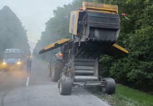 maszyna rolnicza na poboczu drogi, w tle widać policjanta i radiowozy