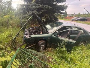 rozbite zielone Renault stojący w rowie z przodem w rozwalonym ogrodzeniu