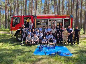 zdjęcie grupowe policjantów i strażaków z harcerzami na tle wozu strażackiego
