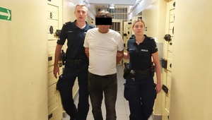 Mężczyzna prowadzony przez umundurowanych policjantów