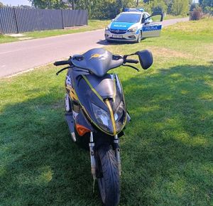 motorower stoi poza drogą. Za nim na ulicy stoi radiowóz