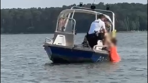 Kadr z filmu na którym widać jak policjanci wyciągają z wody tonącą kobietę.