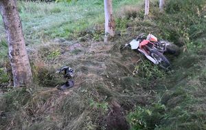 Leżący w rowie przy drzewach uszkodzony motocykl