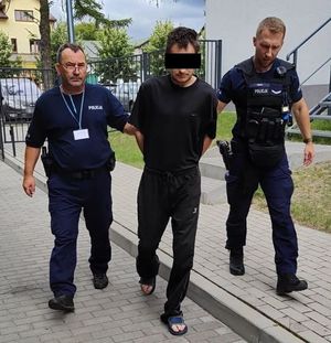 policjanci prowadzą zatrzymanego mężczyznę