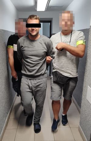 policjanci po cywilnemu prowadzą korytarzem zatrzymanego 37-latka