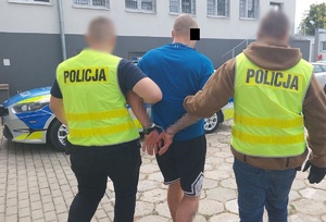 Policjanci prowadzą zatrzymanego mężczyznę.
