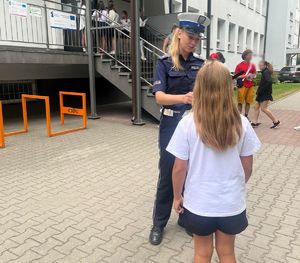 policjantka rozdaje odblaski pod szkołą