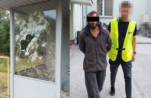 zdjęcie uszkodzonej wiaty, policjant prowadzi zatrzymanego mężczyznę