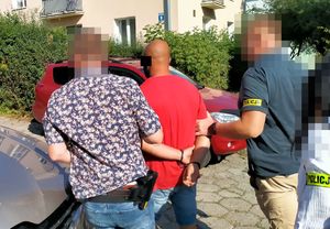 policjanci prowadzą zatrzymanego mężczyznę