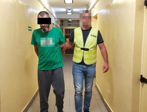 policjant doprowadza zatrzymanego