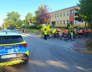 patrol policji pod szkołą rozmawia z uczniami na rowerach