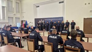 kryminalni siedzący w ławkach, przed nimi organizatorzy konkursu w szeregu