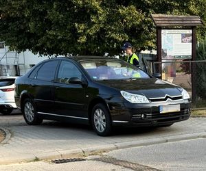 czarny citroen przy bramie, obok policjantka, która kontroluje kierującego