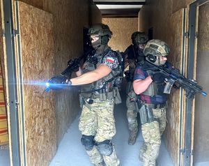 wejście policjantów do budynku z wyciągniętą bronia