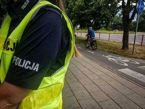 ręka policjantki a w tle jadący rowerem mężczyzna