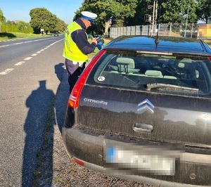 policjant z miernikiem prędkości przy kontrolowanym aucie