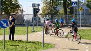 policjantka z dziećmi na miasteczku ruchu drogowego